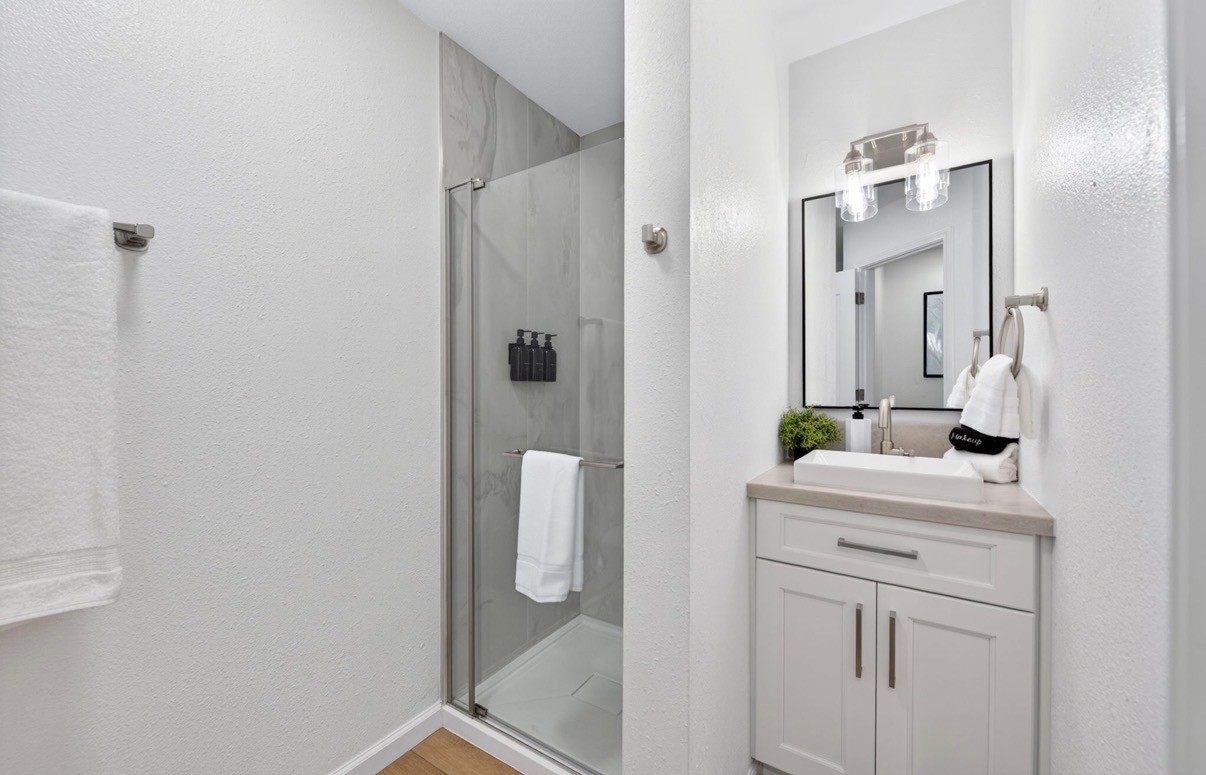 Bass Lake stand-up shower with marble-look walls and adjacent vessel-sink vanity