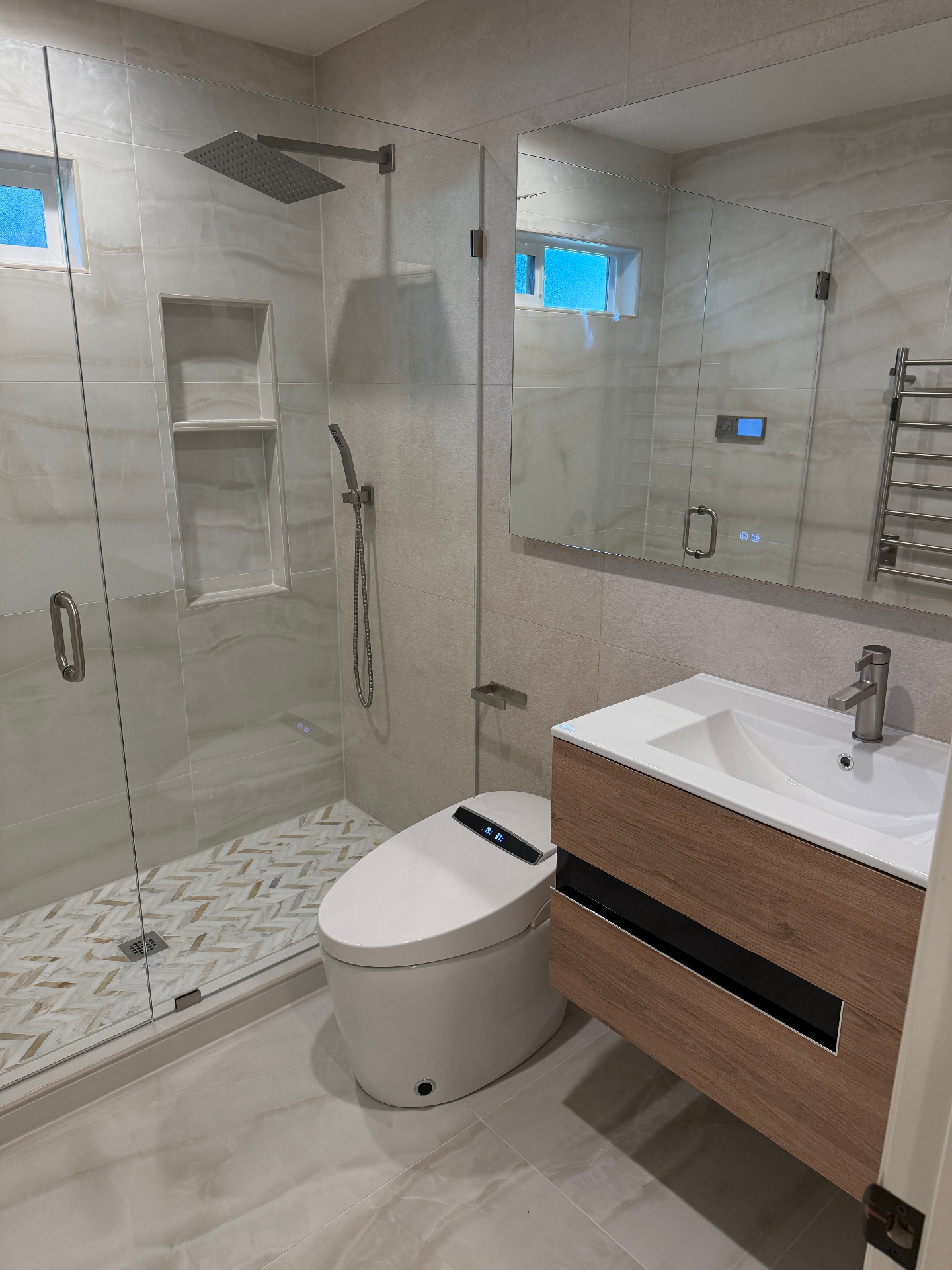 Finished beige bathroom with floating wood-look vanity, smart toilet, and frameless glass shower