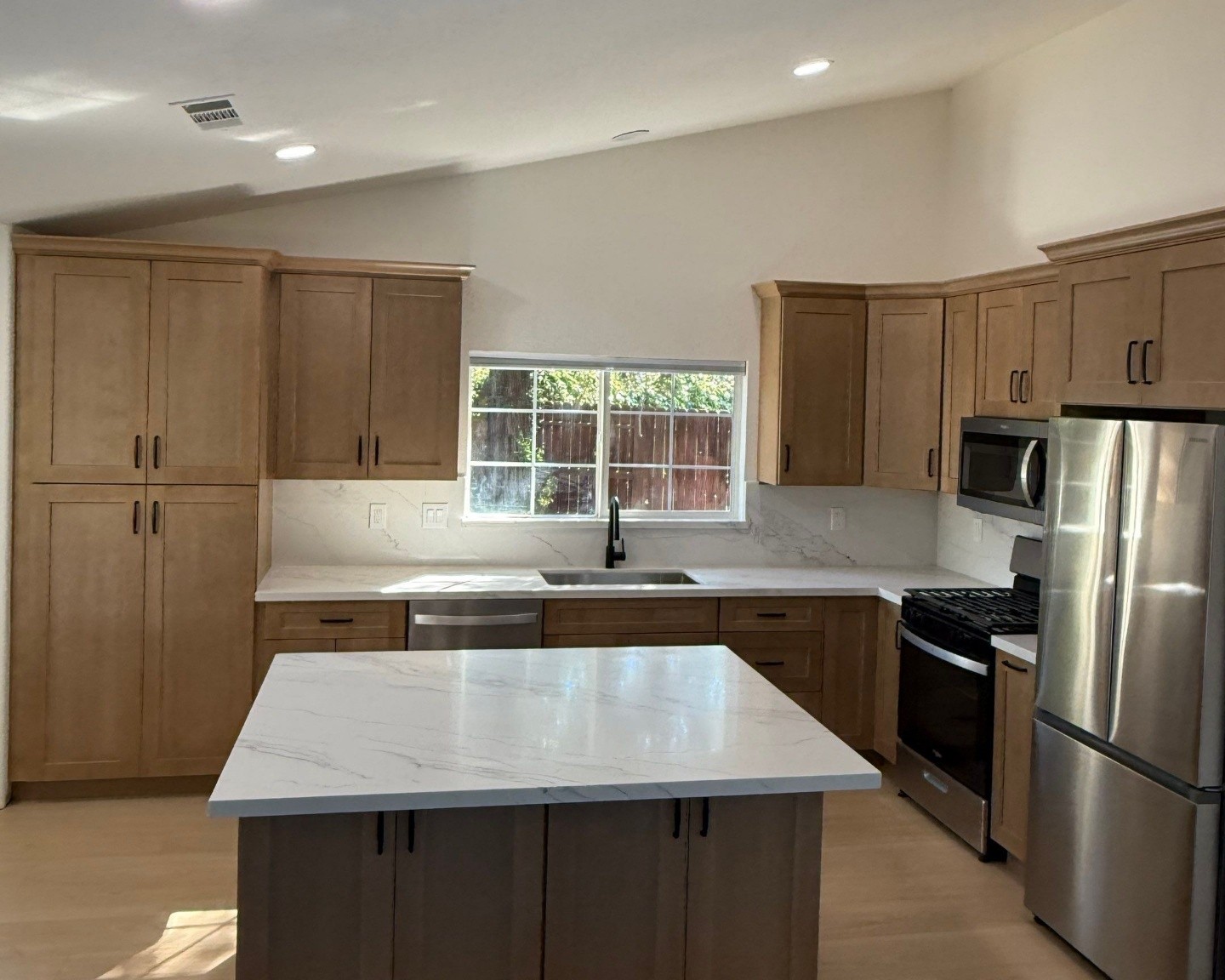 Maple shaker kitchen with white quartz island, farmhouse sink, and stainless appliances